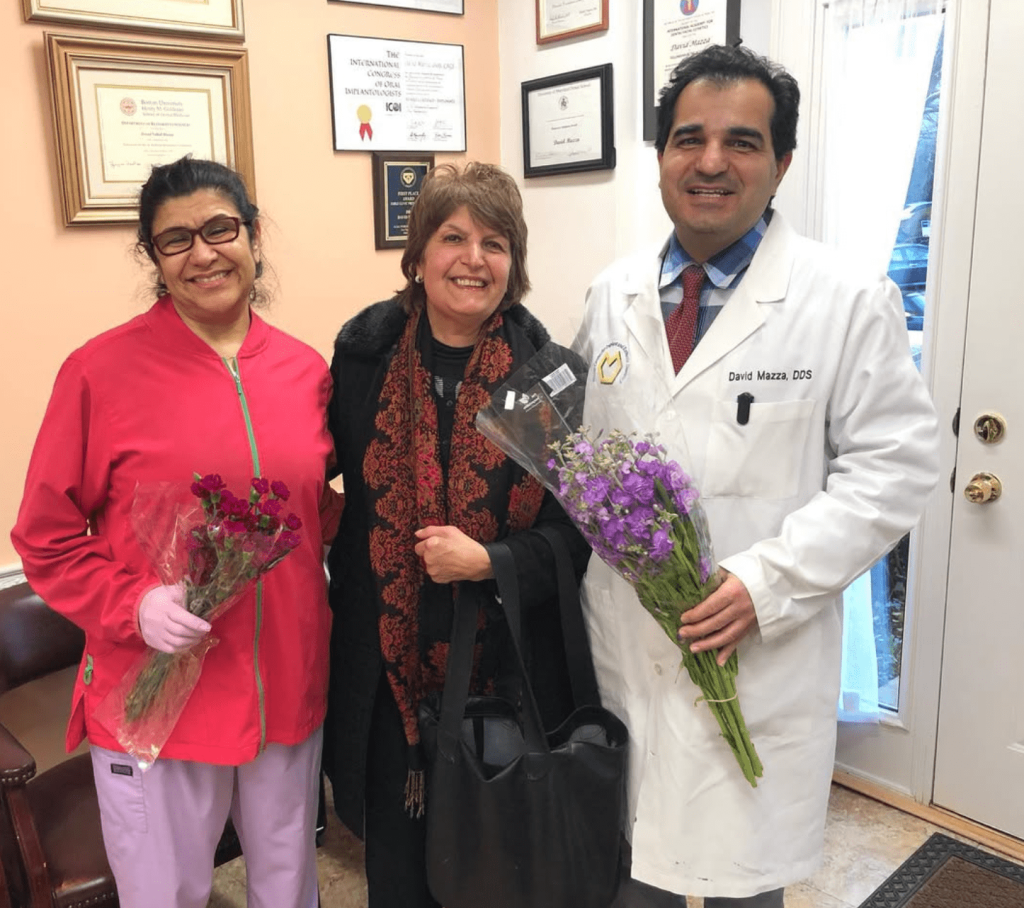 Dr. David Mazza with a patient and team member at his Bethesda dental practice Dr. David Mazza standing with a patient and dental team member holding flowers in Bethesda, MD