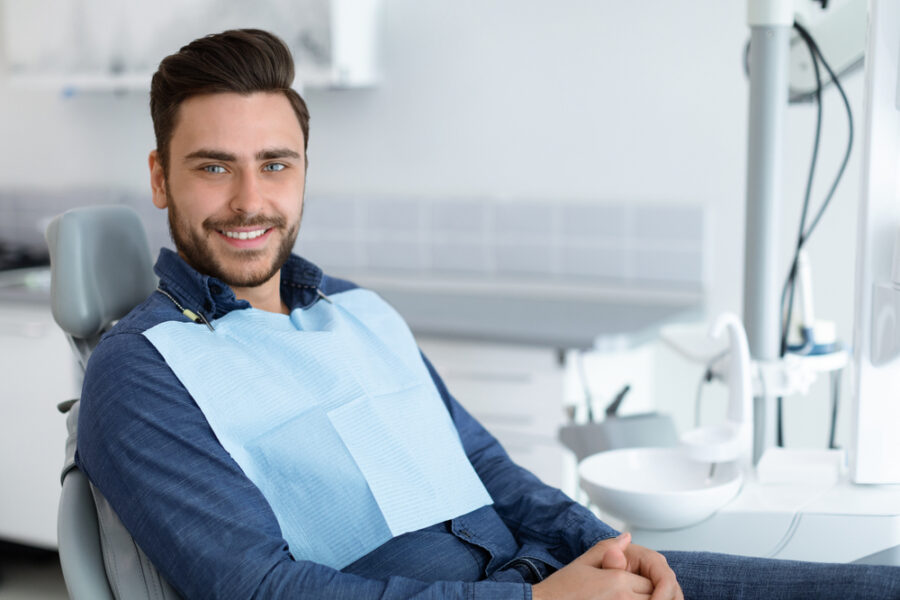Smiling male dental patient wearing a protective bib while seated in a treatment chair at a cosmetic dentistry office in Bethesda, MD