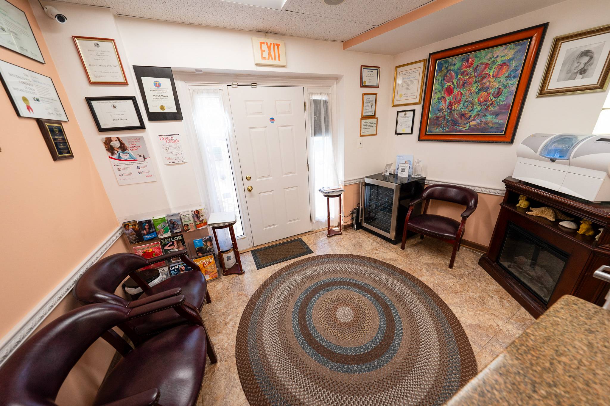 Waiting area at Mazza Center for Implant and Aesthetic Dentistry in Bethesda, MD Reception and waiting area with seating, framed credentials, artwork, and dental equipment in Bethesda, MD