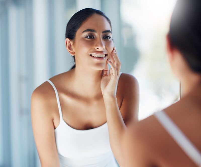 Woman admiring her smile in the mirror after a cosmetic dental transformation in Bethesda, MD