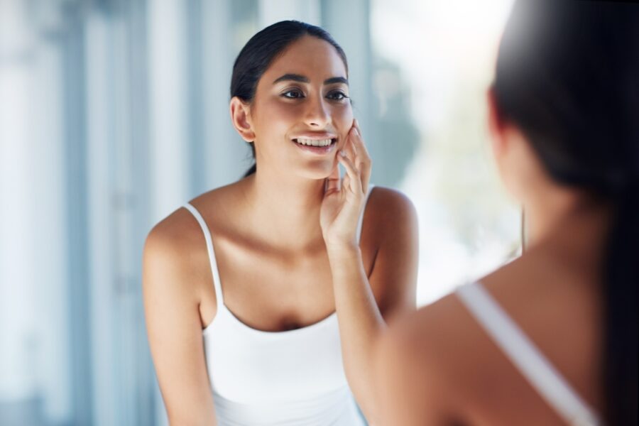 Woman admiring her smile in the mirror after a cosmetic dental transformation in Bethesda, MD